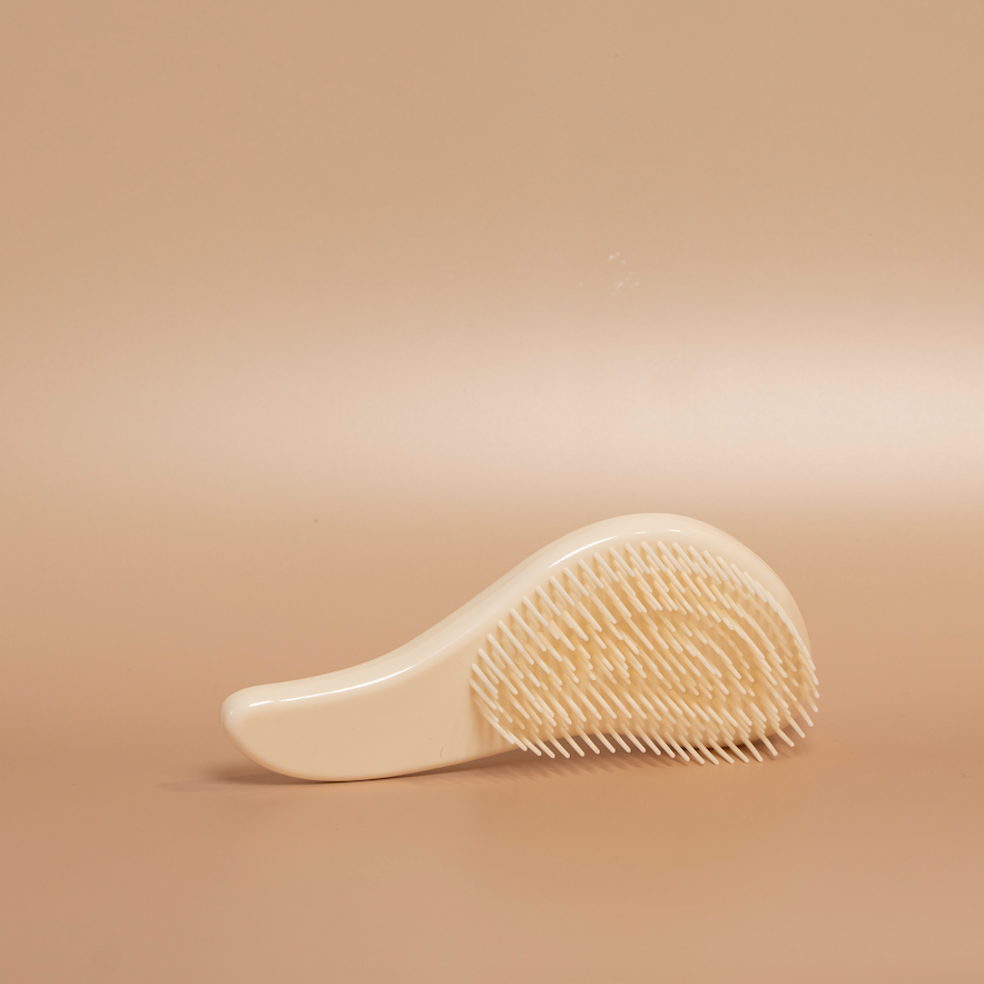 Beige ROYAL detangling hair brush photographed against a beige background.