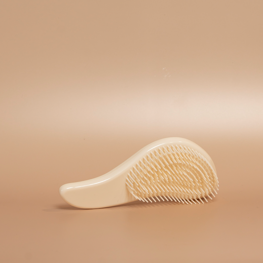 Beige ROYAL detangling hair brush photographed against a beige background.