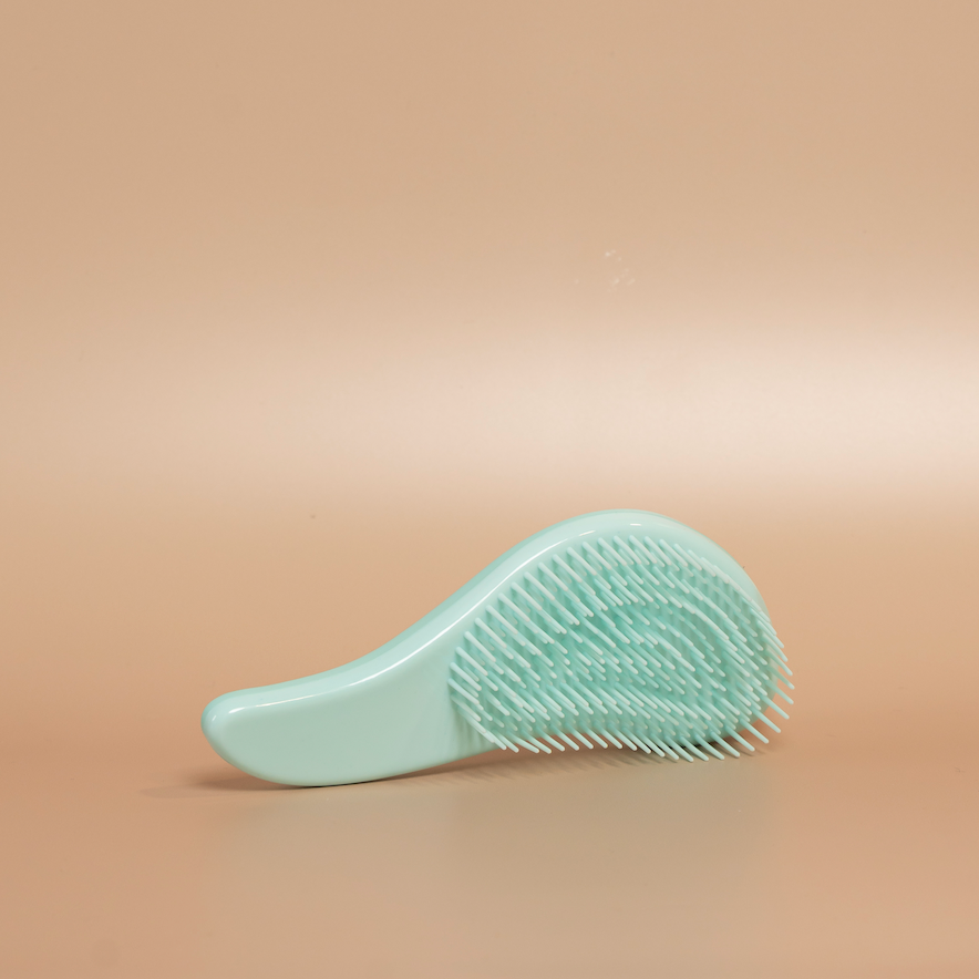 Blue ROYAL detangling hair brush photographed against a beige background.