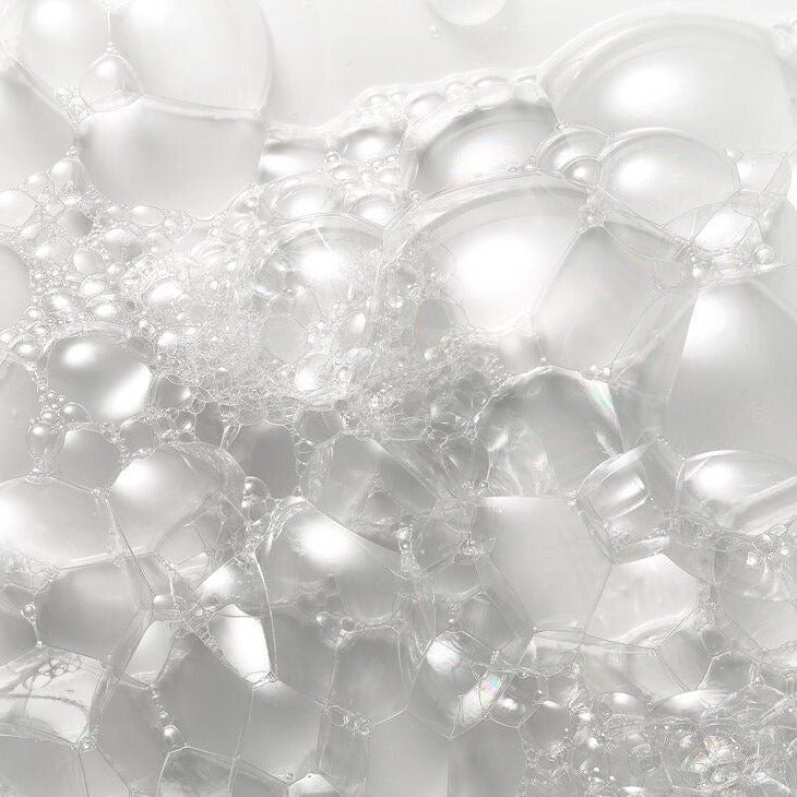 Close-up of translucent cleansing bubbles and foam showcasing a lightweight haircare formula texture.