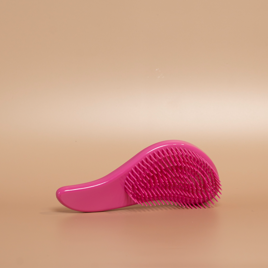 Deep pink ROYAL detangling hair brush photographed against a beige background.