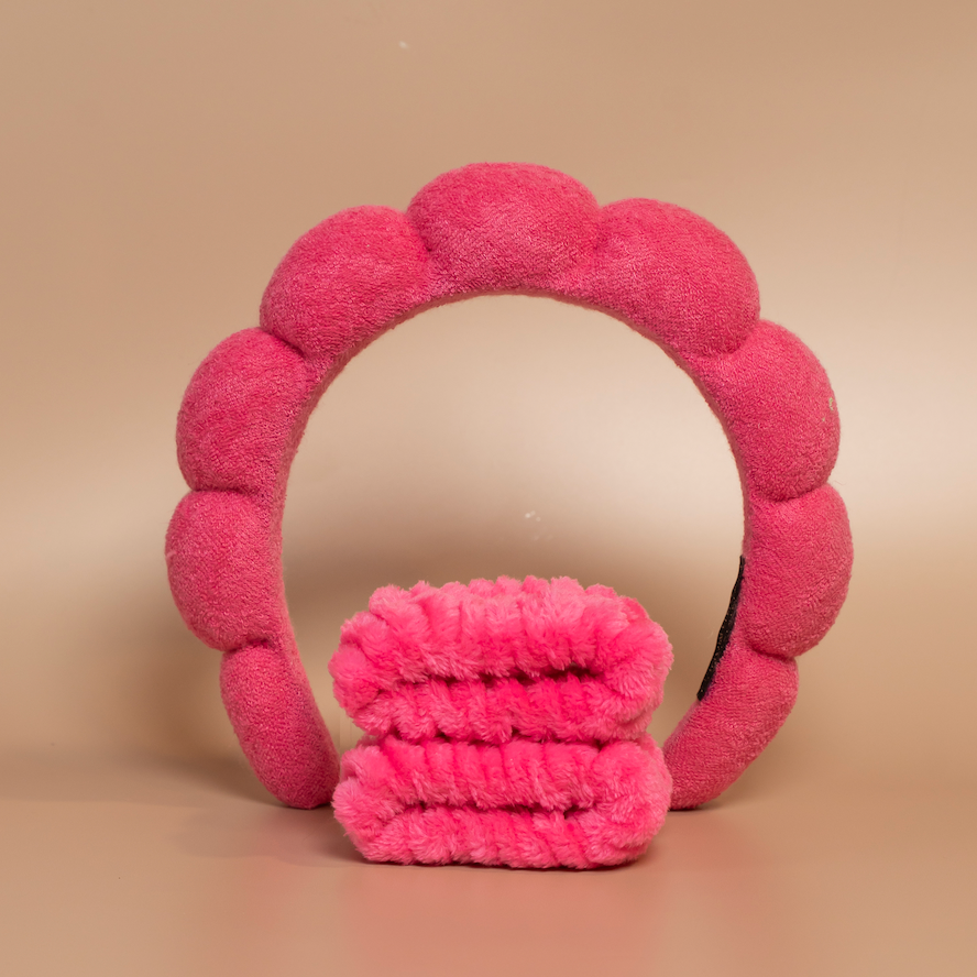 Deep pink ROYAL hair care headband and matching fabric wristbands displayed together against a beige background.