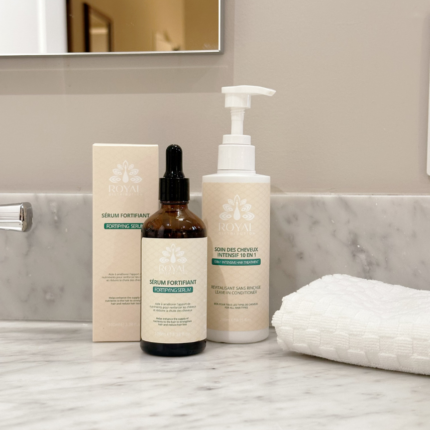 ROYAL Fortifying Serum with its packaging and 10-in-1 Intensive Hair Treatment displayed on a marble bathroom counter.