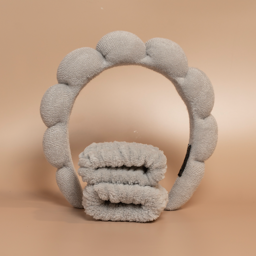 Grey ROYAL hair care headband and matching fabric wristbands displayed together against a beige background.