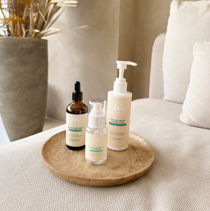 ROYAL Fortifying Serum, Macadamia Hydrating Oil and 10-in-1 Intensive Hair Treatment displayed on a wooden tray in a neutral interior.