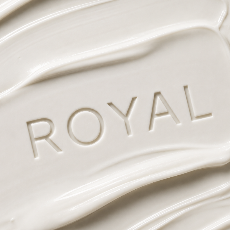 Close-up of a creamy white hair mask texture with the ROYAL name embossed in the product.