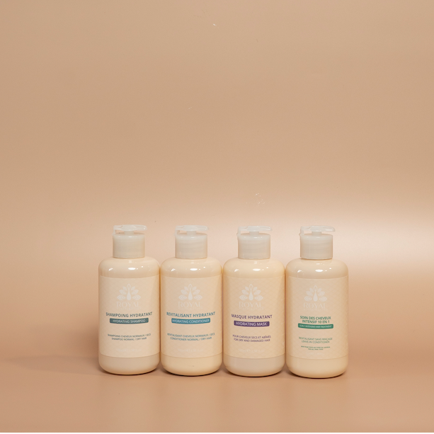 ROYAL Hydrating Travel Hair Care Set featuring 100 ml Hydrating Shampoo, Conditioner, and Hair Mask, plus a 75 ml Intensive 10-in-1 Hair Care, photographed against a beige background.
