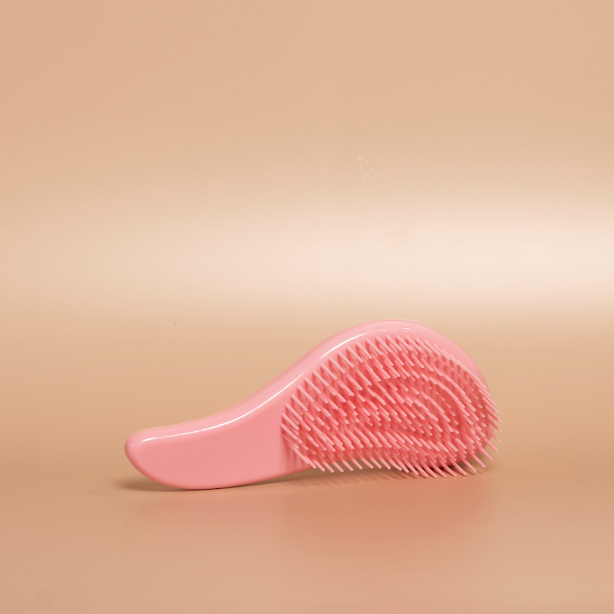 Light pink ROYAL detangling hair brush photographed against a beige background.