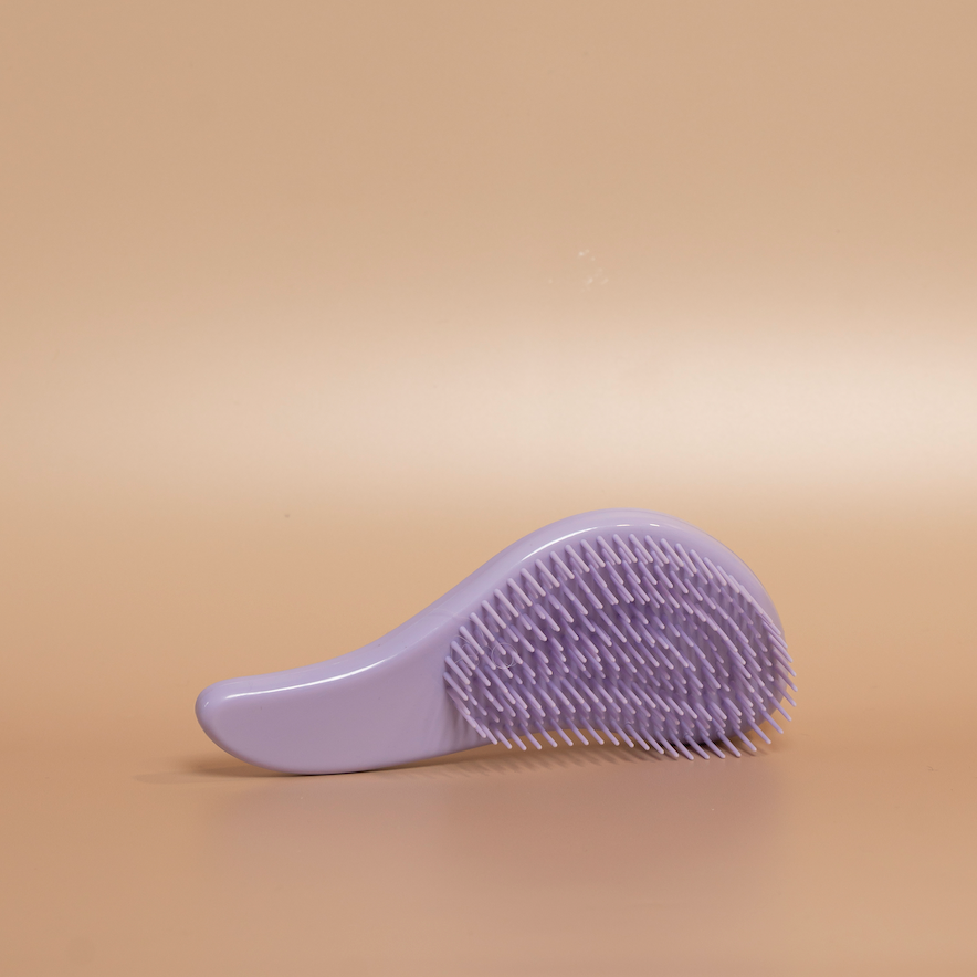 Lilac ROYAL detangling hair brush photographed against a beige background.
