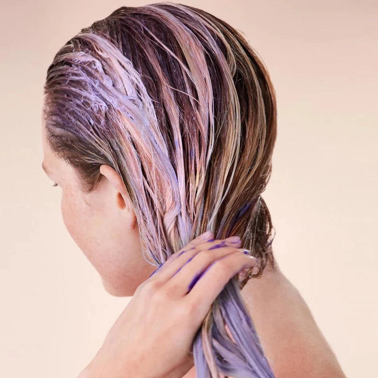 Wet hair coated with a purple-toned haircare formula during a platinum hair maintenance routine.