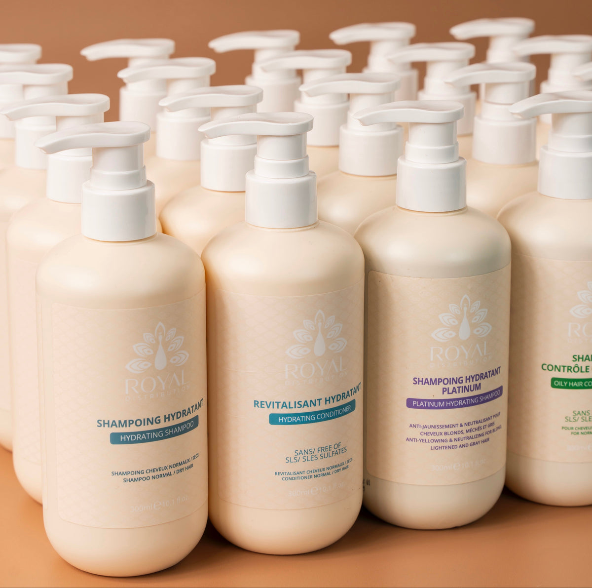 Selection of ROYAL professional hair care products in 300 ml bottles, including hydrating, conditioning, platinum and oil-control formulas, arranged on a warm beige background.