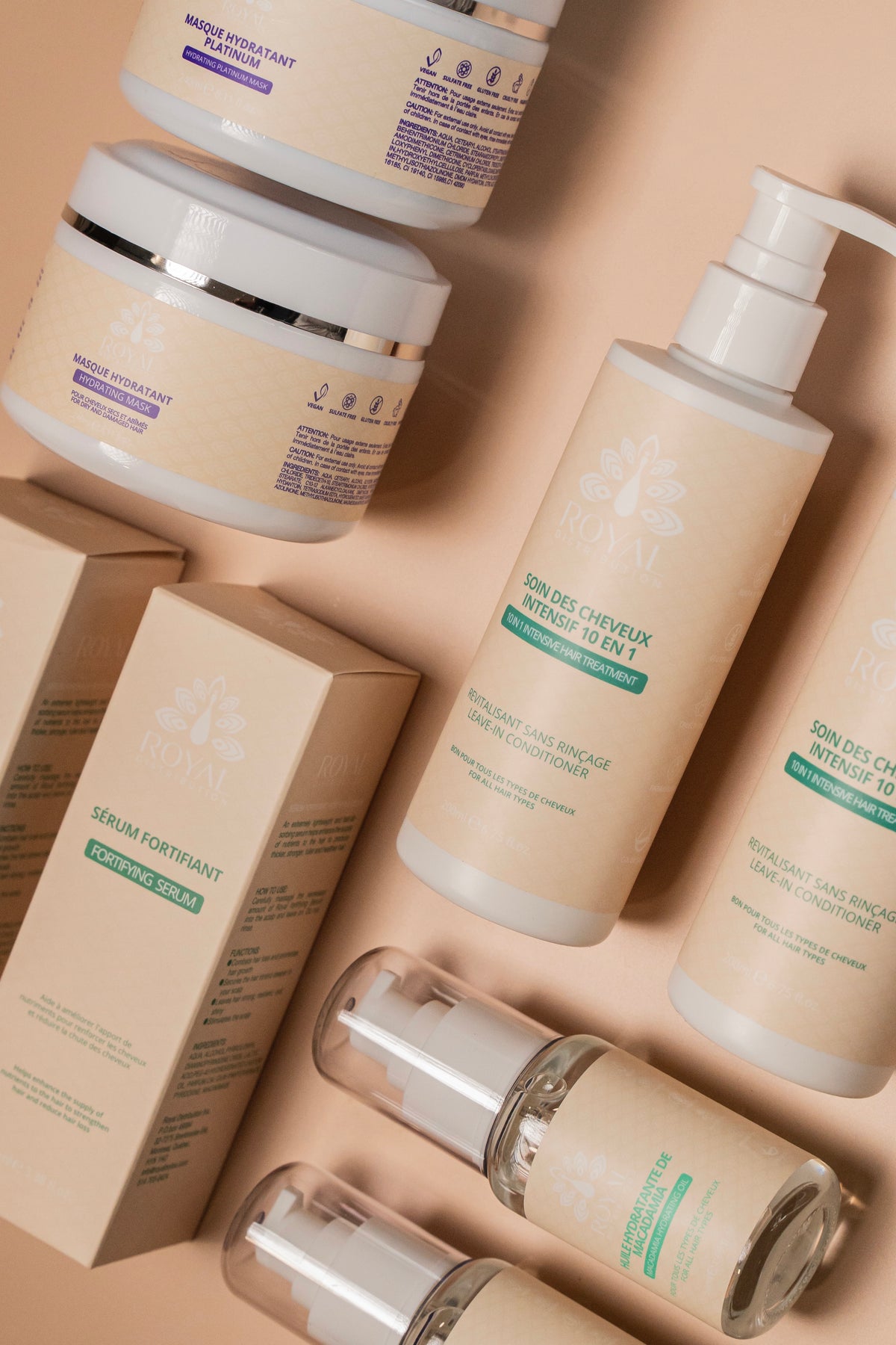 Selection of ROYAL hair care products including hydrating masks, leave-in conditioners, Fortifying Serum and Macadamia Hydrating Oil arranged on a warm beige background.