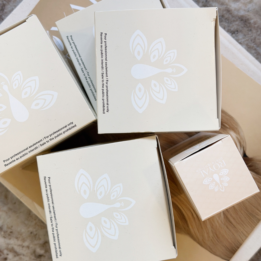 ROYAL professional hair treatment boxes arranged in a neutral editorial setting, featuring the ROYAL peacock emblem and professional-only packaging.