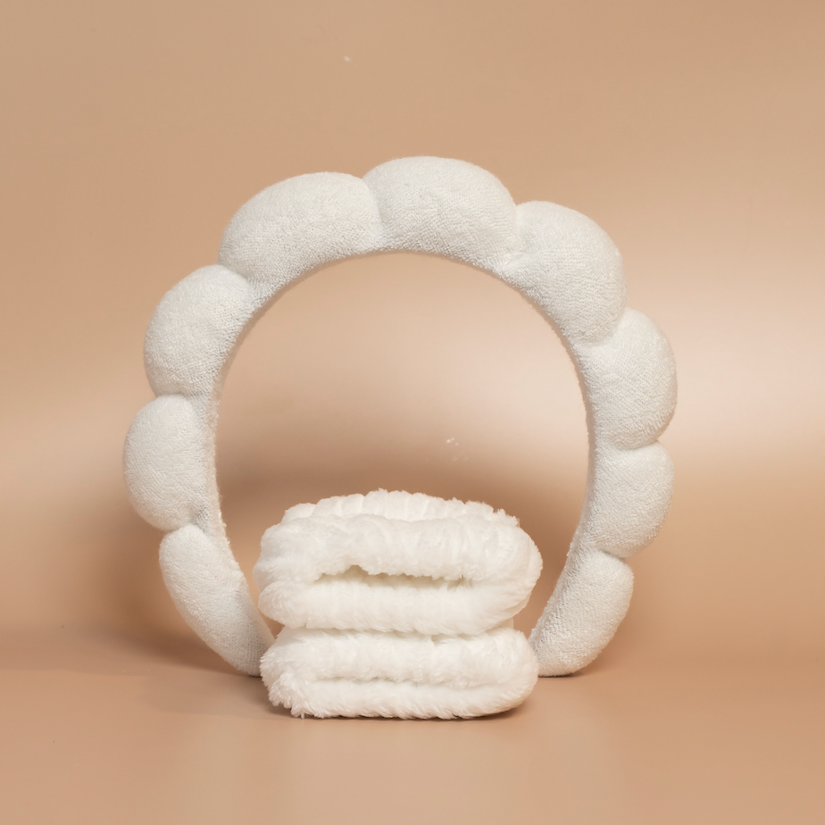 White ROYAL hair care headband and matching fabric wristbands displayed together against a beige background.
